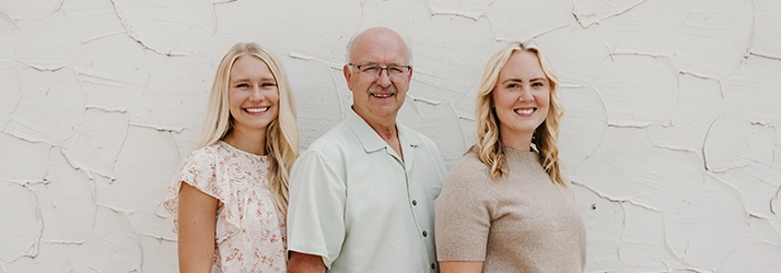 Chiropractors Kayla Naess, Kenneth Ruf, And Rae Beaver Smiling In Front Of White Wall Mobile